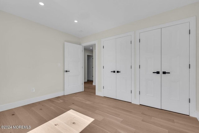 unfurnished bedroom with multiple closets and light hardwood / wood-style flooring