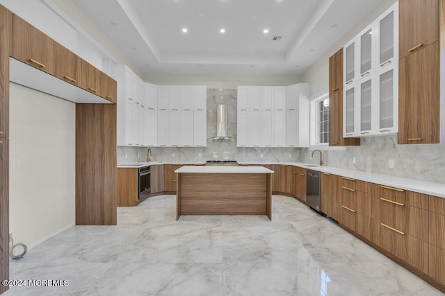 kitchen with a center island, backsplash, sink, wall chimney exhaust hood, and appliances with stainless steel finishes