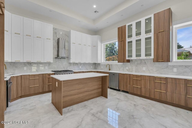 kitchen featuring wall chimney exhaust hood, a center island, plenty of natural light, and white cabinetry