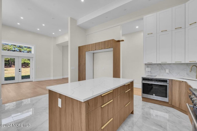 kitchen featuring a center island, french doors, white cabinets, sink, and stainless steel appliances