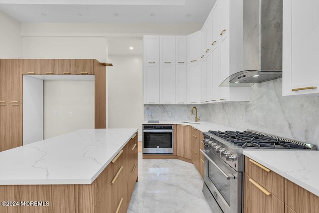 kitchen featuring backsplash, wall chimney exhaust hood, appliances with stainless steel finishes, light stone counters, and white cabinetry