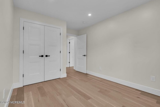 unfurnished bedroom with light wood-type flooring and a closet