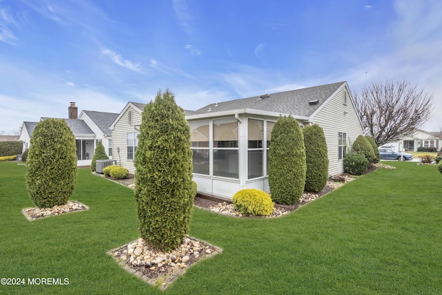 view of side of property featuring a yard, central AC, and a sunroom