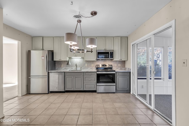 kitchen with tasteful backsplash, gray cabinetry, stainless steel appliances, sink, and hanging light fixtures