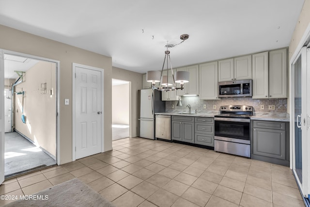 kitchen with hanging light fixtures, stainless steel appliances, tasteful backsplash, gray cabinets, and light tile patterned flooring