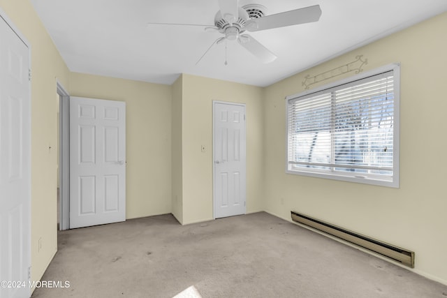 unfurnished bedroom with ceiling fan, a closet, light colored carpet, and a baseboard heating unit