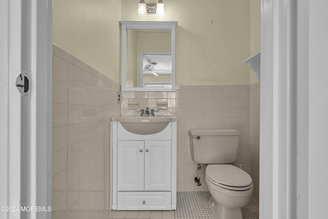 bathroom with tile patterned flooring, vanity, toilet, and tile walls