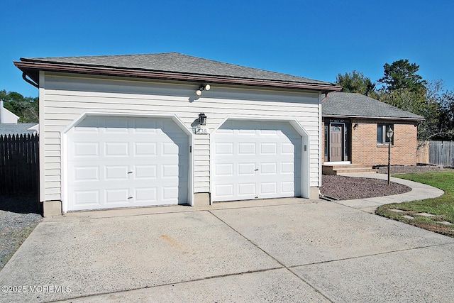 view of front of home with a shingled roof, driveway, an attached garage, and fence