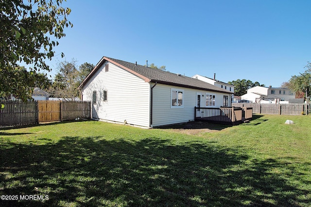 back of house featuring a lawn, a wooden deck, and a fenced backyard