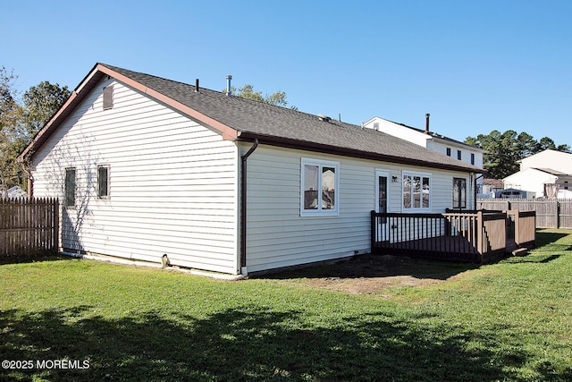 back of property featuring a shingled roof, a yard, a wooden deck, and fence