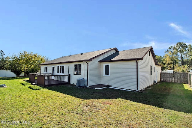 back of property with a fenced backyard, a yard, a deck, and central air condition unit