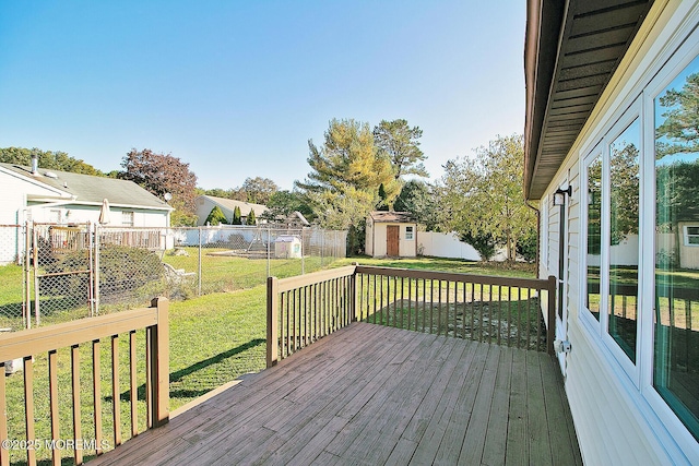 deck with a fenced backyard, an outdoor structure, a lawn, and a storage unit