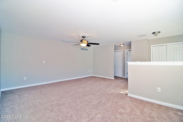 carpeted spare room with baseboards, visible vents, and ceiling fan