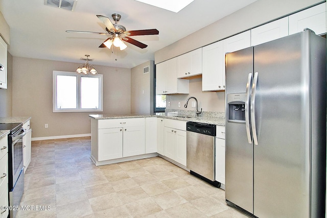 kitchen with stainless steel appliances, a peninsula, a sink, and white cabinets