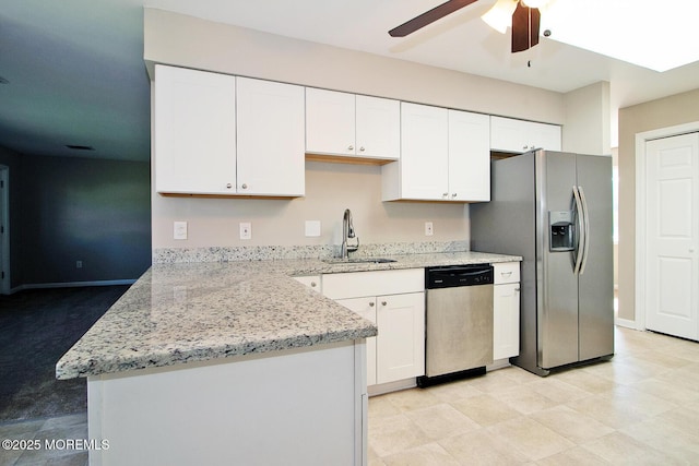 kitchen with light stone counters, a peninsula, a sink, white cabinetry, and appliances with stainless steel finishes