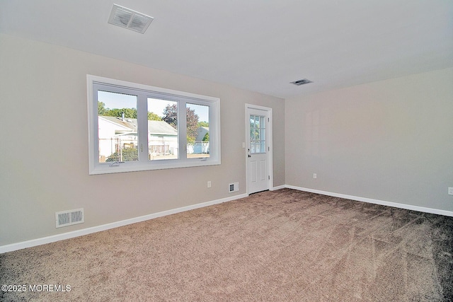 empty room with baseboards, visible vents, and carpet flooring