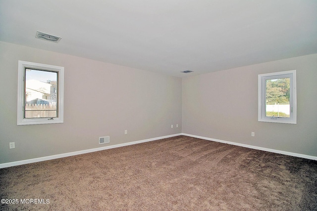 spare room featuring carpet flooring, visible vents, and baseboards