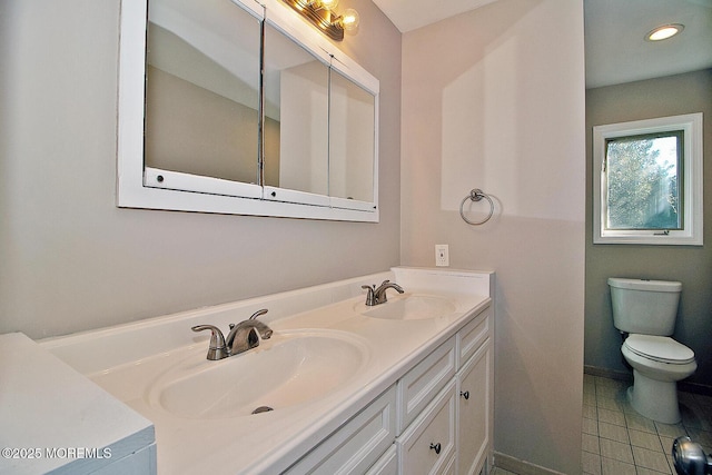 bathroom featuring double vanity, tile patterned flooring, a sink, and toilet