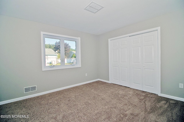 unfurnished bedroom featuring carpet floors, baseboards, visible vents, and a closet