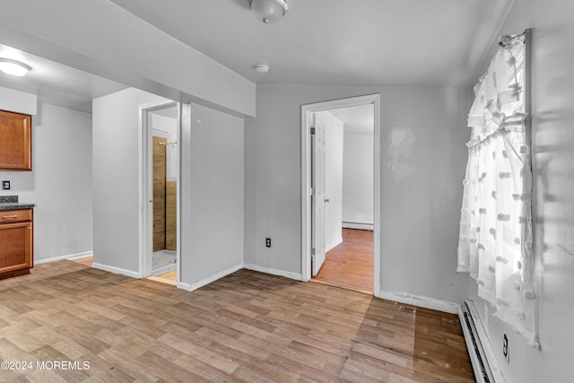 interior space featuring a baseboard heating unit, lofted ceiling, and light hardwood / wood-style flooring