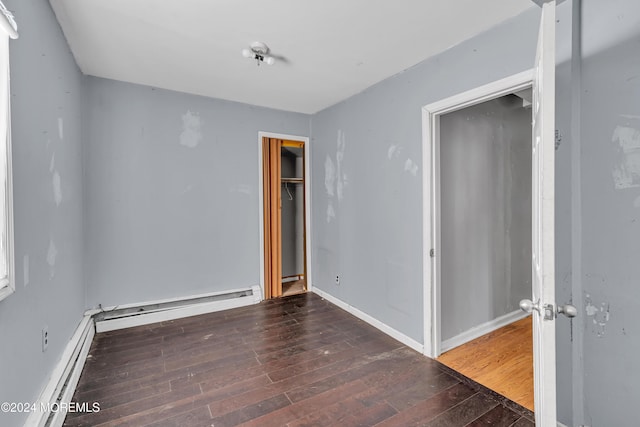 unfurnished room featuring a baseboard radiator and dark hardwood / wood-style floors