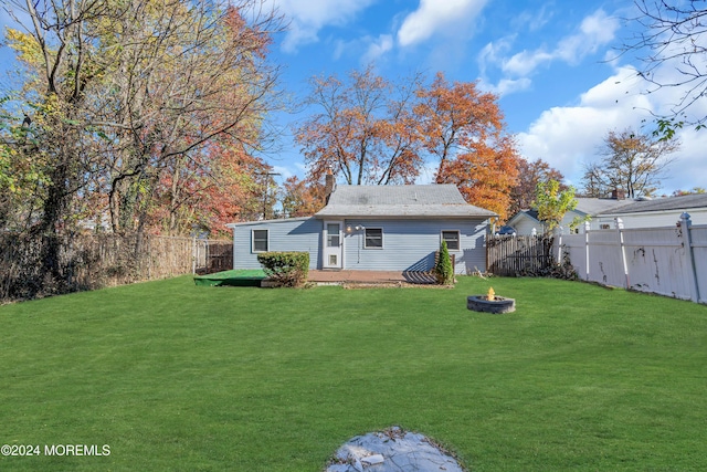 rear view of property with a fire pit and a lawn