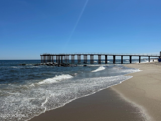 view of dock with a water view and a view of the beach