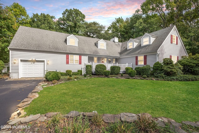 cape cod house featuring a lawn, a porch, and a garage