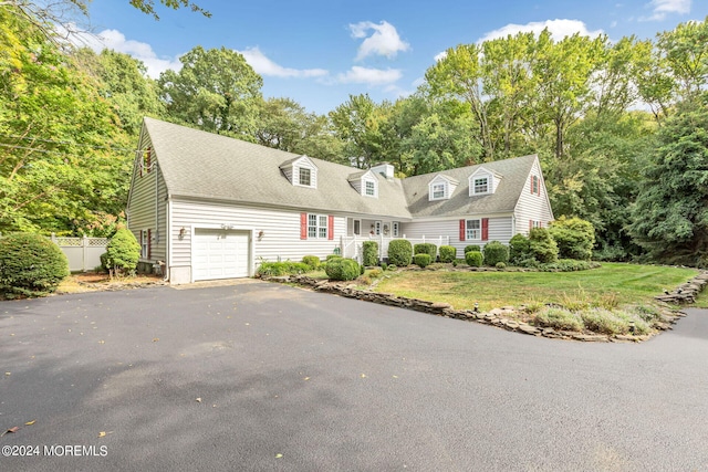 cape cod house with a garage and a front lawn