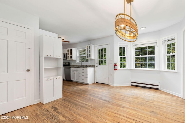 kitchen with a healthy amount of sunlight, white cabinetry, hanging light fixtures, and a baseboard radiator