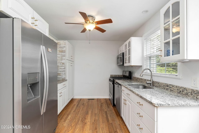 kitchen with light stone countertops, stainless steel appliances, sink, light hardwood / wood-style floors, and white cabinetry