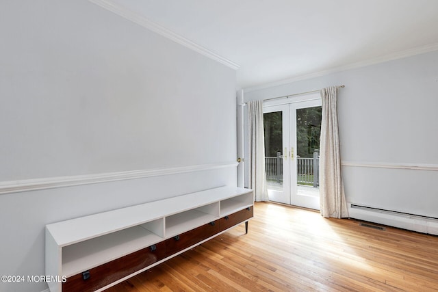 empty room featuring a baseboard heating unit, light wood-type flooring, ornamental molding, and french doors