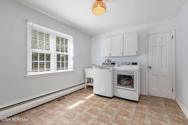 clothes washing area with cabinets, washing machine and clothes dryer, sink, and a baseboard heating unit