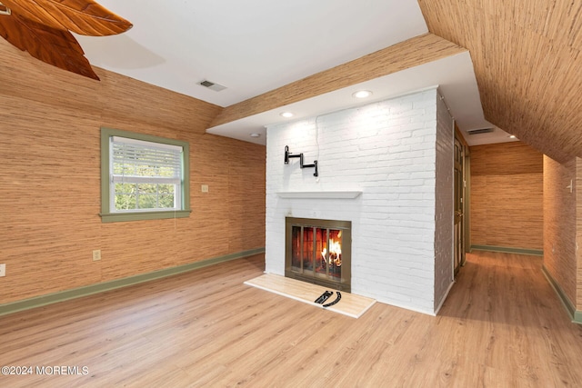 unfurnished living room with hardwood / wood-style flooring, lofted ceiling, and a fireplace