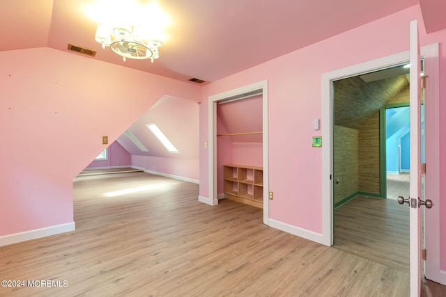 bonus room featuring a notable chandelier, lofted ceiling, and light wood-type flooring