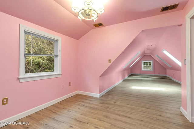 additional living space with light hardwood / wood-style floors and lofted ceiling with skylight