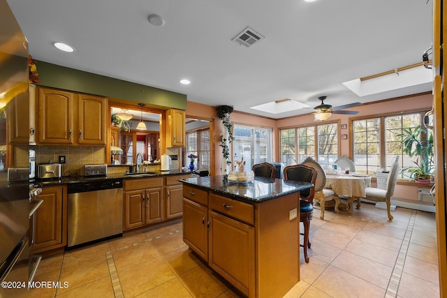 kitchen with dishwasher, a skylight, ceiling fan, light tile patterned floors, and a kitchen island