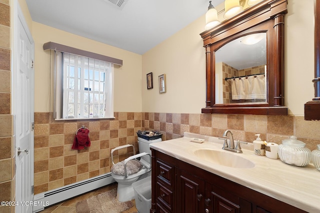 bathroom featuring vanity, toilet, baseboard heating, and tile walls