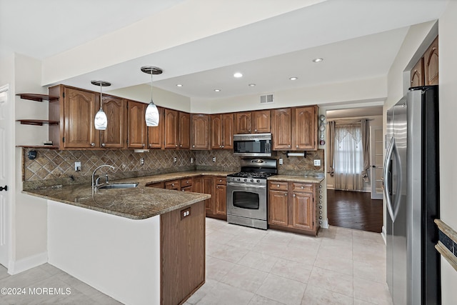 kitchen with sink, tasteful backsplash, kitchen peninsula, pendant lighting, and appliances with stainless steel finishes