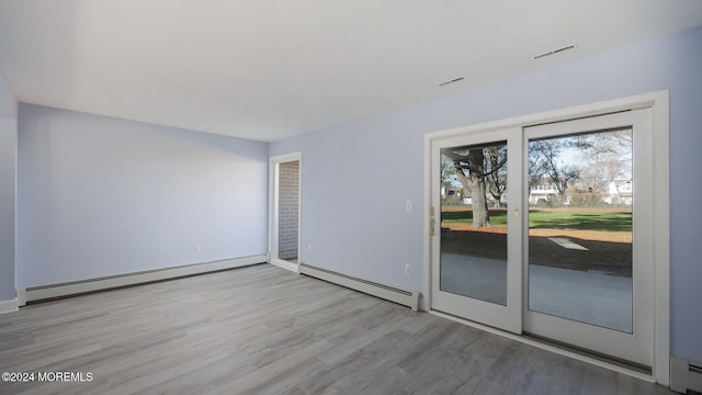 unfurnished room with baseboard heating and light wood-type flooring