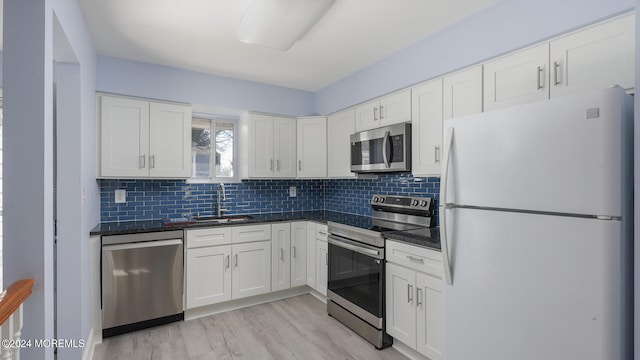 kitchen with sink, light hardwood / wood-style flooring, tasteful backsplash, white cabinetry, and stainless steel appliances