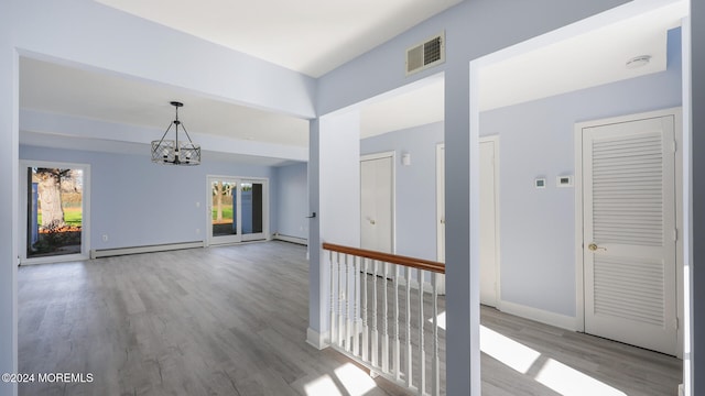 hallway featuring a notable chandelier, light wood-type flooring, and baseboard heating