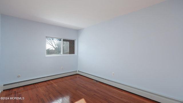 unfurnished room featuring wood-type flooring and a baseboard radiator