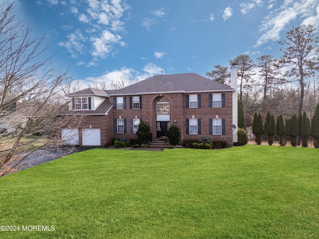 colonial-style house featuring a garage and a front yard