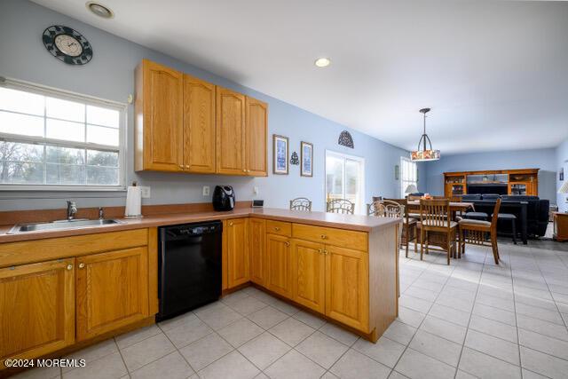 kitchen with kitchen peninsula, sink, pendant lighting, light tile patterned floors, and black dishwasher