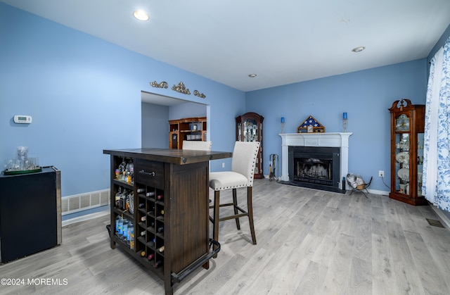 bar with dark brown cabinetry and light hardwood / wood-style flooring