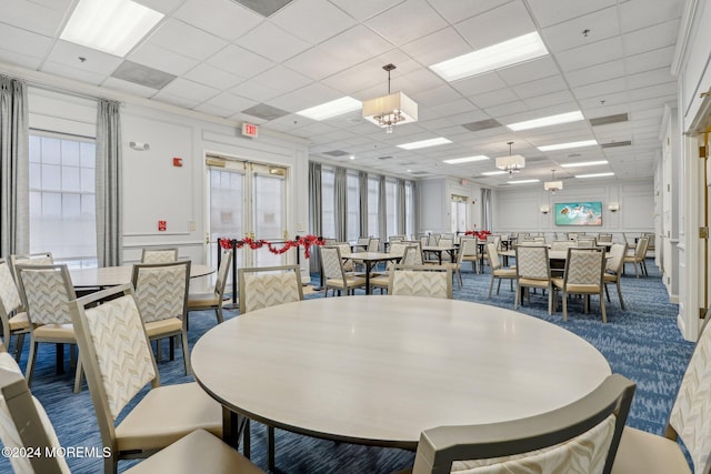 dining space featuring carpet flooring and a drop ceiling