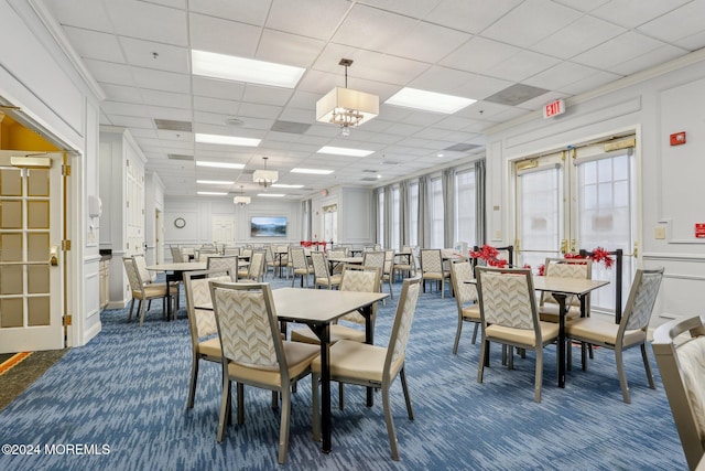 dining space featuring dark carpet, a drop ceiling, and ornamental molding