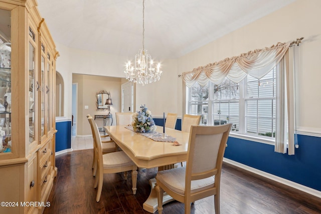 dining area with dark hardwood / wood-style floors and an inviting chandelier