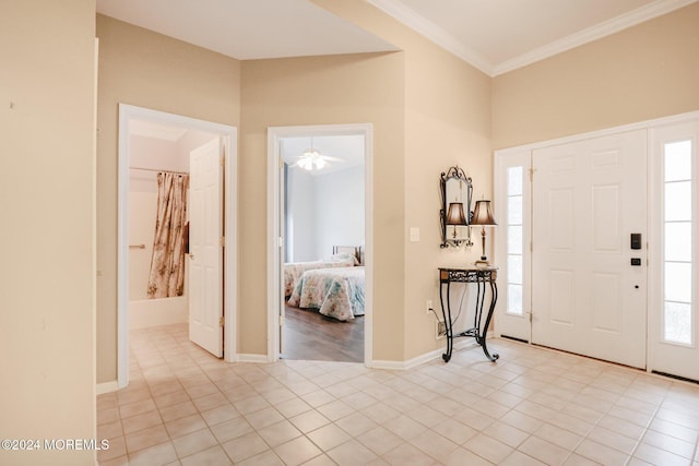 tiled foyer featuring crown molding and ceiling fan